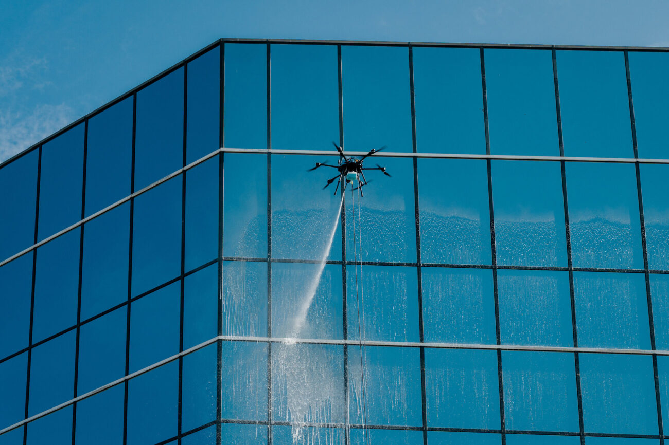 Lucid Bots Sherpa Drone spraying windows at height with the power tether